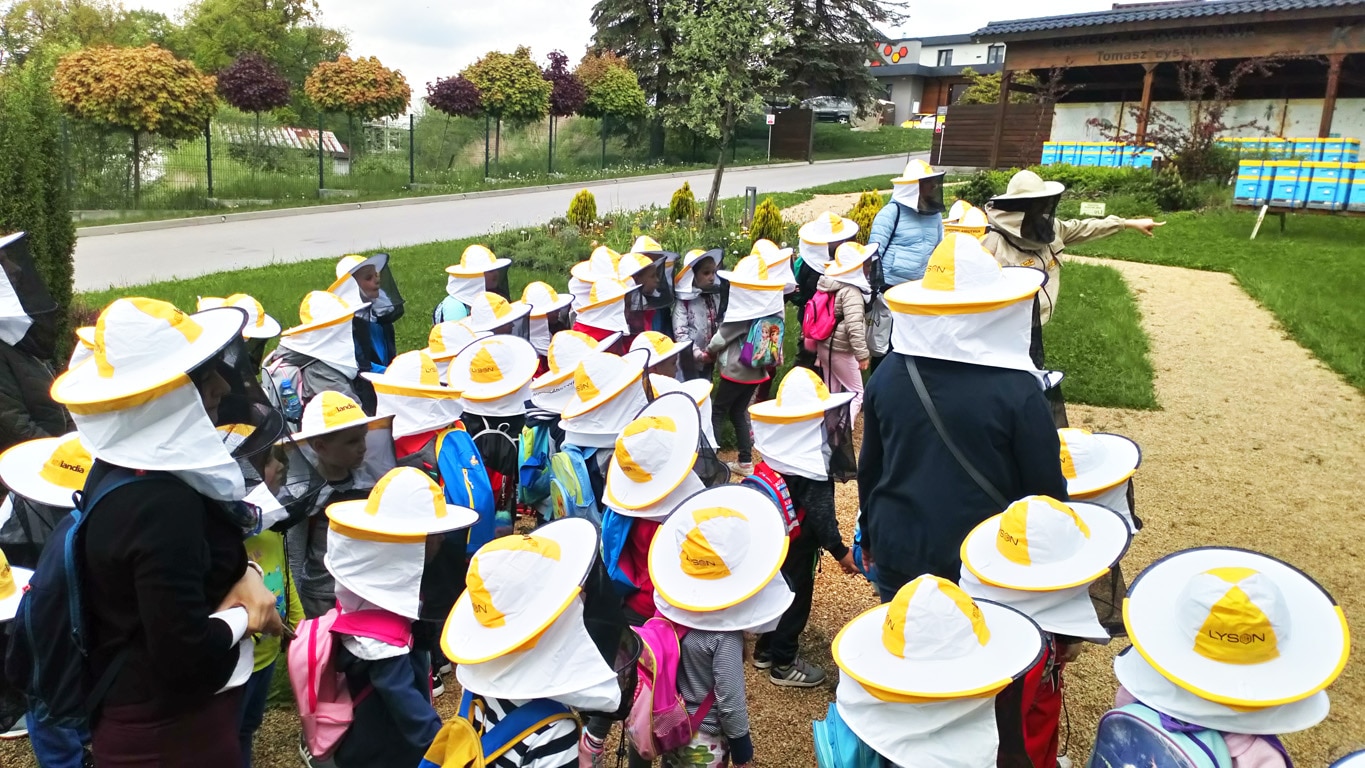 Grupa dzieci w czapkach pszczelarskich